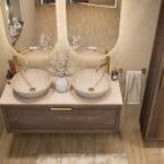 Hangend donker eiken wastafelmeubel 120 cm met enkele lade en limestone blad met twee witte waskommen