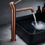 Moderne hoge wastafelkraan in geborsteld koper voor een badmeubel met waskom, geleverd als complete set inclusief bijpassende clickwaste met duurzame PVD-coating. De clickwaste is een handige pop-up afvoer die je eenvoudig opent en sluit door erop te