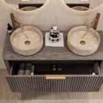 Rond hangend donker eiken wastafelmeubel 120 cm met groevenfront en twee beige marmerlook waskommen
