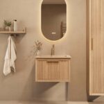 Het Riva badkamermeubel 60 in naturel eiken combineert ambachtelijk vakmanschap met moderne luxe. Gemaakt van massief eiken met ribbelfront, softclose lades en een mat beige Mineraalsteen wastafel. De wastafel kan met of zonder kraangaten worden gele