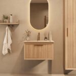 Het Riva badkamermeubel 70 in naturel eiken combineert ambachtelijk vakmanschap met moderne luxe. Gemaakt van massief eiken met ribbelfront, softclose lades en een mat beige Mineraalsteen wastafel. De wastafel kan met of zonder kraangaten worden gele