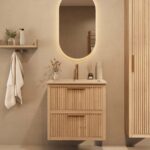 Het Riva badkamermeubel 70 in naturel eiken combineert ambachtelijk vakmanschap met moderne luxe. Gemaakt van massief eiken met ribbelfront, twee softclose lades en een mat beige Mineraalsteen wastafel. De wastafel kan met of zonder kraangaten worden