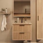 Het Riva badkamermeubel 80 in naturel eiken combineert ambachtelijk vakmanschap met moderne luxe. Gemaakt van massief eiken met ribbelfront, twee softclose lades en een mat beige Mineraalsteen wastafel. De wastafel kan met of zonder kraangaten worden
