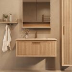 Het Riva badkamermeubel 100 in naturel eiken combineert ambachtelijk vakmanschap met moderne luxe. Gemaakt van massief eiken met ribbelfront, softclose lades en een mat beige Mineraalsteen wastafel. De wastafel kan met of zonder kraangaten worden gel