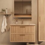 Het Riva badkamermeubel 100 in naturel eiken combineert ambachtelijk vakmanschap met moderne luxe. Gemaakt van massief eiken met ribbelfront, twee softclose lades en een mat beige Mineraalsteen wastafel. De wastafel kan met of zonder kraangaten worde