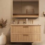 Het Riva badkamermeubel 120 in naturel eiken combineert ambachtelijk vakmanschap met moderne luxe. Gemaakt van massief eiken met ribbelfront, twee softclose lades en een mat beige dubbele Mineraalsteen wastafel. De wastafel kan met of zonder kraangat