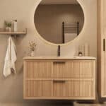 Het Riva badkamermeubel 120 in naturel eiken combineert ambachtelijk vakmanschap met moderne luxe. Gemaakt van massief eiken met ribbelfront, twee softclose lades en een mat beige Mineraalsteen wastafel. De wastafel kan met of zonder kraangaten worde