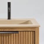 Het Riva badkamermeubel 160 in naturel eiken combineert ambachtelijk vakmanschap met moderne luxe. Gemaakt van massief eiken met ribbelfront, vier softclose lades en een mat beige dubbele Mineraalsteen wastafel. De wastafel kan met of zonder kraangat