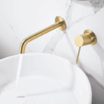 Moderne muurwastafelkraan in geborsteld goud voor wandmontage boven een wastafel of waskom, geleverd als complete set inclusief bijpassende clickwaste met duurzame PVD-coating. De clickwaste is een handige pop-up afvoer die je eenvoudig opent en slui