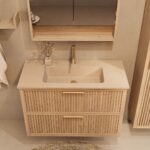 Het Riva badkamermeubel 100 in naturel eiken combineert ambachtelijk vakmanschap met moderne luxe. Gemaakt van massief eiken met ribbelfront, twee softclose lades en een mat beige Mineraalsteen wastafel. De wastafel kan met of zonder kraangaten worde