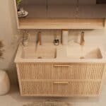 Het Riva badkamermeubel 120 in naturel eiken combineert ambachtelijk vakmanschap met moderne luxe. Gemaakt van massief eiken met ribbelfront, twee softclose lades en een mat beige dubbele Mineraalsteen wastafel. De wastafel kan met of zonder kraangat