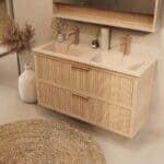 Het Riva badkamermeubel 120 in naturel eiken combineert ambachtelijk vakmanschap met moderne luxe. Gemaakt van massief eiken met ribbelfront, twee softclose lades en een mat beige dubbele Mineraalsteen wastafel. De wastafel kan met of zonder kraangat