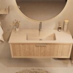 Het Riva badkamermeubel 120 in naturel eiken combineert ambachtelijk vakmanschap met moderne luxe. Gemaakt van massief eiken met ribbelfront, softclose lades en een mat beige Mineraalsteen wastafel. De wastafel kan met of zonder kraangaten worden gel