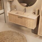 Het Riva badkamermeubel 120 in naturel eiken combineert ambachtelijk vakmanschap met moderne luxe. Gemaakt van massief eiken met ribbelfront, softclose lades en een mat beige Mineraalsteen wastafel. De wastafel kan met of zonder kraangaten worden gel