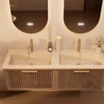 Het Riva badkamermeubel 140 in donker eiken ademt luxe en rust. Massief eiken met groevenfront, hoogwaardige softclose lades en een mat beige Mineraalsteen dubbel wastafel. De wastafel kan met of zonder kraangaten worden geleverd.