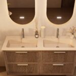 Het Riva badkamermeubel 140 in donker eiken ademt luxe en rust. Massief eiken met groevenfront, vier hoogwaardige softclose lades en een mat beige Mineraalsteen dubbele wastafel. De wastafel kan met of zonder kraangaten worden geleverd.