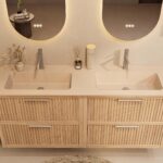 Het Riva badkamermeubel 160 in naturel eiken combineert ambachtelijk vakmanschap met moderne luxe. Gemaakt van massief eiken met ribbelfront, vier softclose lades en een mat beige dubbele Mineraalsteen wastafel. De wastafel kan met of zonder kraangat