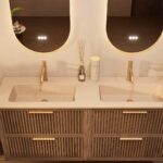 Het Riva badkamermeubel 160 in Donker eiken combineert ambachtelijk vakmanschap met moderne luxe. Gemaakt van massief eiken met ribbelfront, vier softclose lades en een mat beige dubbele Mineraalsteen wastafel. De wastafel kan met of zonder kraangate