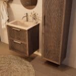 Het Riva badkamermeubel 60 in donker eiken ademt luxe en rust. Massief eiken met groevenfront, twee hoogwaardige softclose lades en een mat beige Mineraalsteen wastafel. De wastafel kan met of zonder kraangaten worden geleverd.