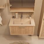 Het Riva badkamermeubel 80 in naturel eiken combineert ambachtelijk vakmanschap met moderne luxe. Gemaakt van massief eiken met ribbelfront, softclose lades en een mat beige Mineraalsteen wastafel. De wastafel kan met of zonder kraangaten worden gele