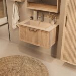 Het Riva badkamermeubel 80 in naturel eiken combineert ambachtelijk vakmanschap met moderne luxe. Gemaakt van massief eiken met ribbelfront, softclose lades en een mat beige Mineraalsteen wastafel. De wastafel kan met of zonder kraangaten worden gele