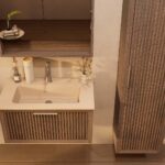 Het Riva badkamermeubel 80 in donker eiken ademt luxe en rust. Massief eiken met groevenfront, hoogwaardige softclose lades en een mat beige Mineraalsteen wastafel. De wastafel kan met of zonder kraangaten worden geleverd.