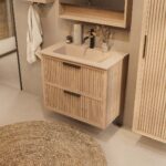 Het Riva badkamermeubel 80 in naturel eiken combineert ambachtelijk vakmanschap met moderne luxe. Gemaakt van massief eiken met ribbelfront, twee softclose lades en een mat beige Mineraalsteen wastafel. De wastafel kan met of zonder kraangaten worden