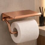 Strakke toiletrolhouder met planchet uit de Grav serie, uitgevoerd in geborsteld koper met duurzame PVD-coating. Het planchet bedekt het toiletpapier en biedt ruimte om kleine accessoires op te plaatsen. Voor wandmontage. De afwerking sluit exact aan