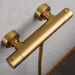 Thermostatische douchekraan in geborsteld goud met duurzame PVD-coating, geleverd als complete set met handdouche, doucheslang van 180 cm en wandhouder. Uit de Riva Bella serie, verkrijgbaar in 6 kleuren en geleverd met 5 jaar garantie.