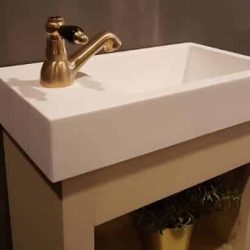 toiletmeubel met keramische wastafel en een gouden fonteinkraan