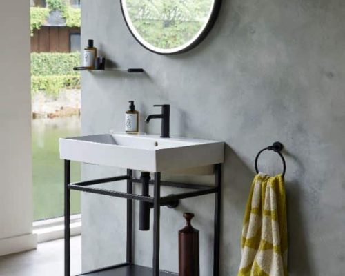 industrieel badkamermeubel op poten met een witte wastafel en een zwarte spiegel