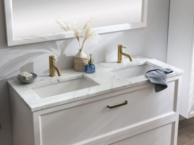 Een badkamer met een wit badkamermeubel, marmeren wastafelblad en gouden kranen in de hotel chique badkamer
