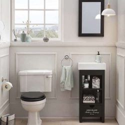 klassieke toiletruimte met daarin een zwarte fonteinkast met een witte wastafel en een zwarte spiegel
