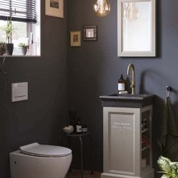 WC meubel met granieten fontein en gouden kraan met bijpassende spiegel met hangend toilet in de toiletruimte