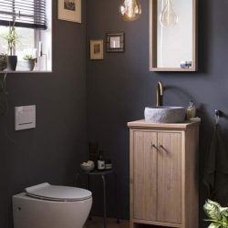 Staand WC meubel van massief eiken met een granieten waskom en gouden kraan. Boven het toiletmeubel is een bijpassende eiken spiegel geplaatst