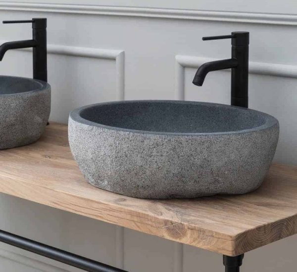 granieten waskom op een badkamermeubel met een zwarte kraan